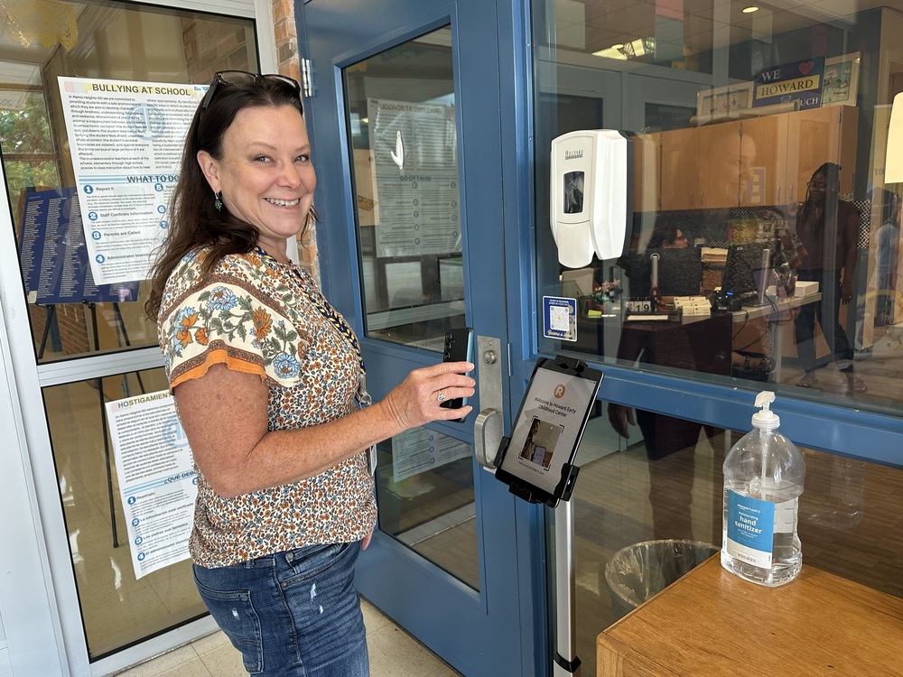 Woman holding up phone to ipad kiosk outside office