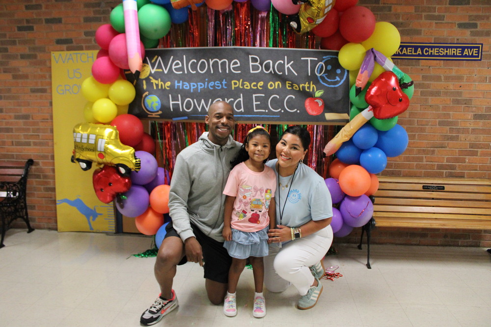 Back to School family poses in front of sign