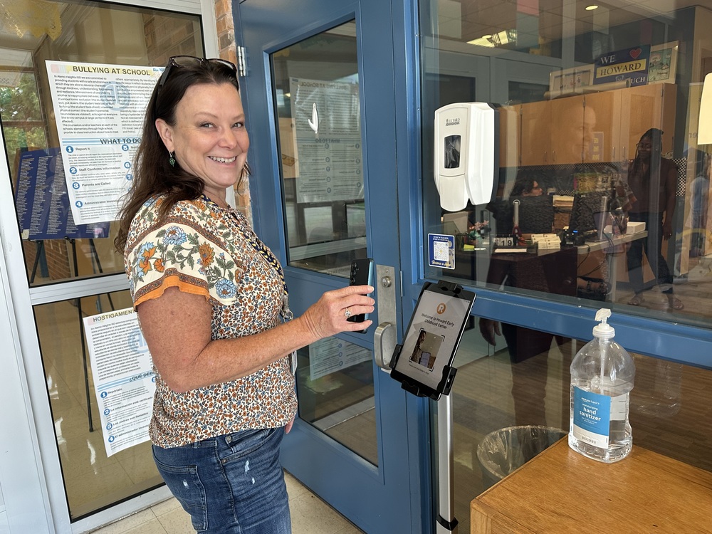 Woman holding up phone to ipad kiosk outside office