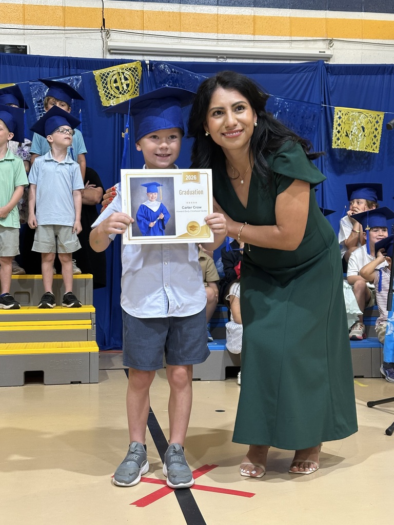 Principal hands certificate to kinder student in cap