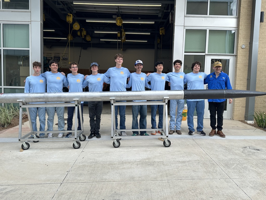 Rocketry students and teacher stand in front of their 21 foot rocket.