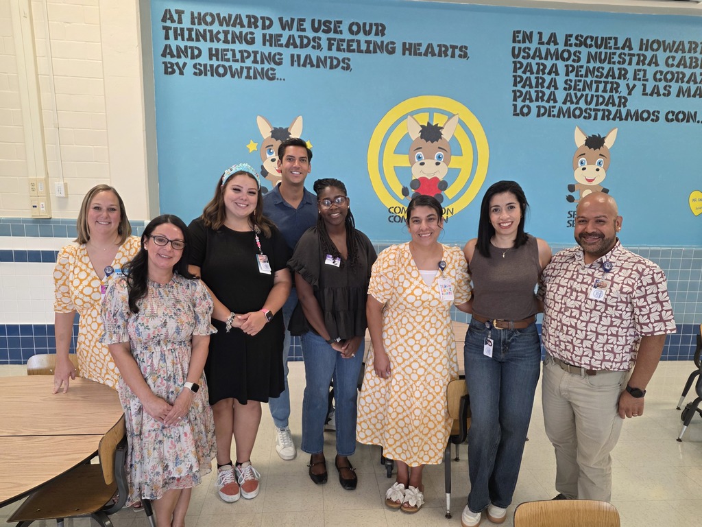 New Howard teachers pose in front of mural in cafeteria