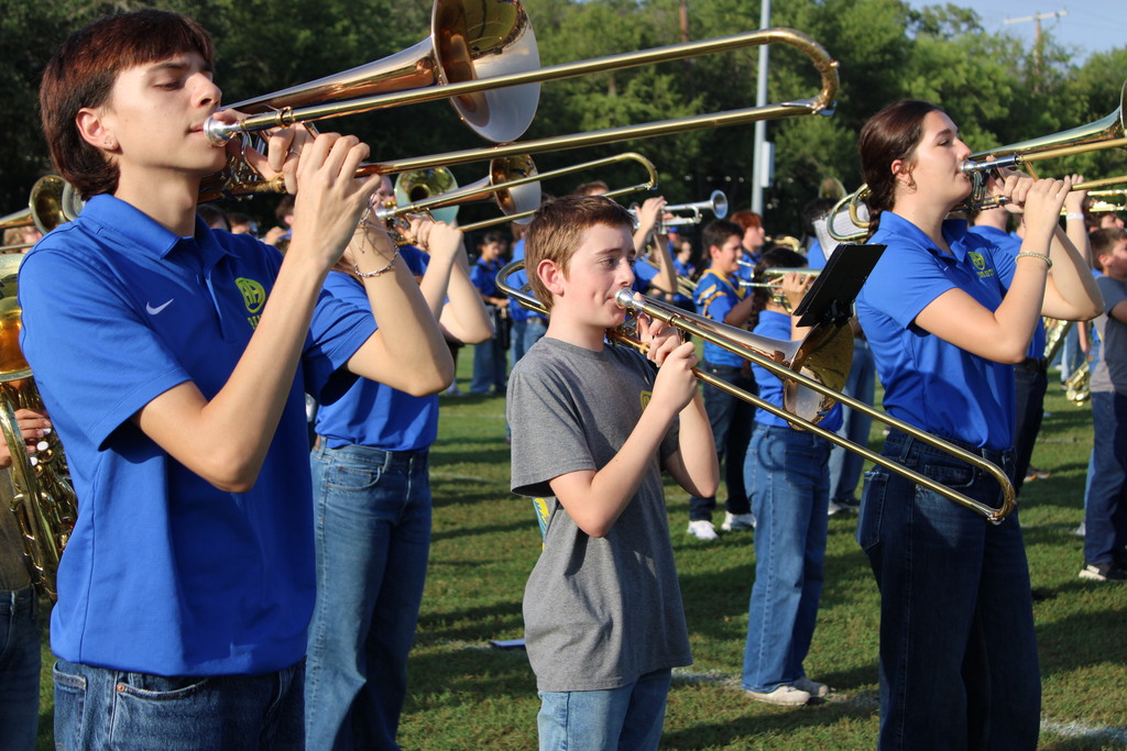 High school and junior school band members perform together on field