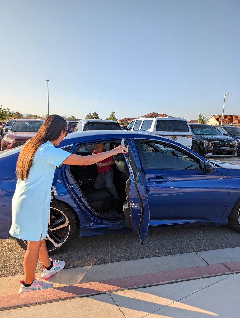Teacher helping parent with school drop off.