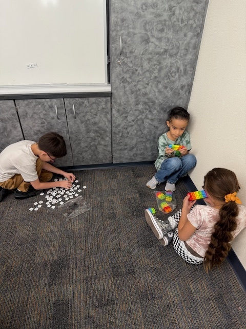 Three students in classroom working with letter popits