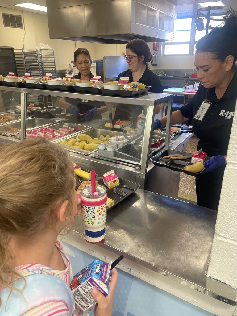 student being served breakfast by staff in kitchen
