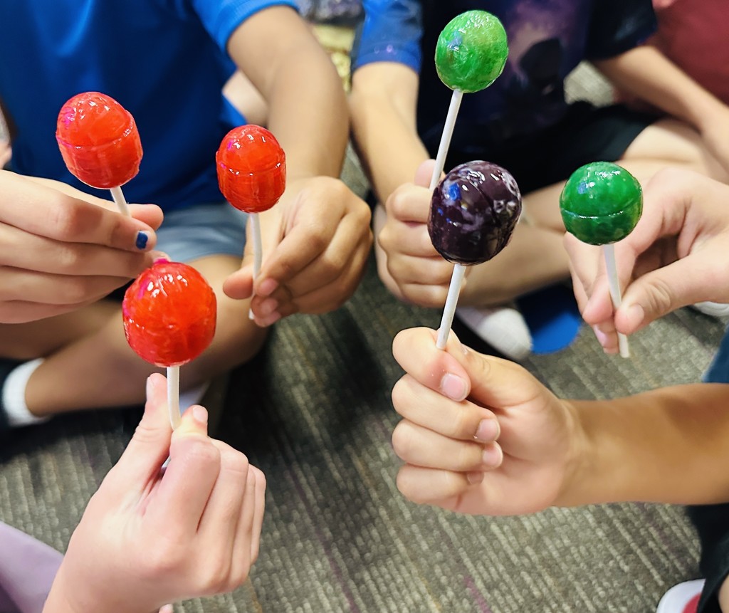 Hands holding Blow Pops in Mrs. Wolfe's class