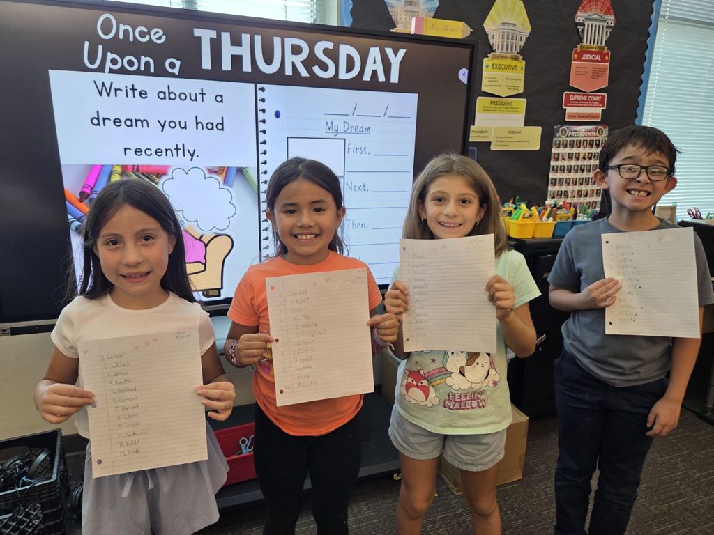 3rd grade students showing off their earned 100% on the VC/CV spelling pattern test,