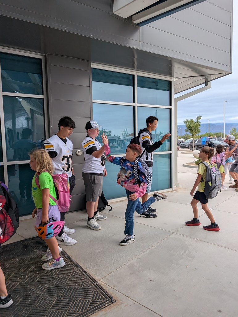 elementary school students greeting highschool football players