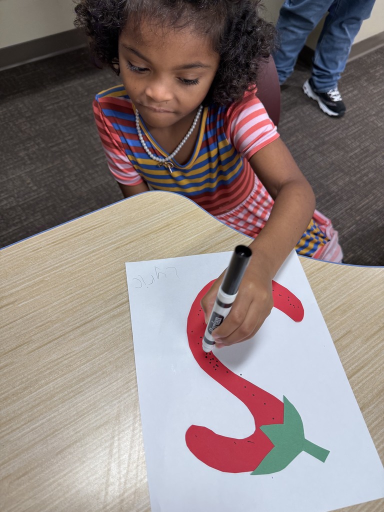 Student is drawing an S that looks like a strawberry.