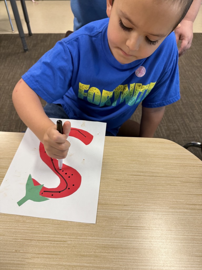Student is drawing an S that looks like a strawberry.