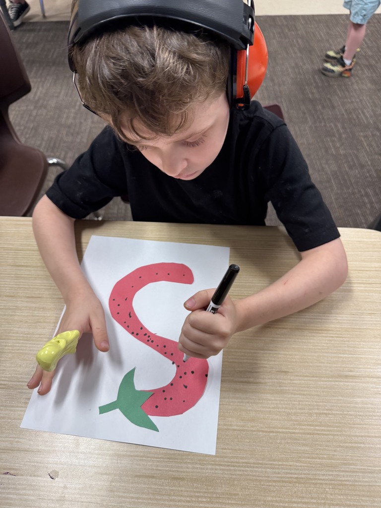 Student is drawing an S that looks like a strawberry.