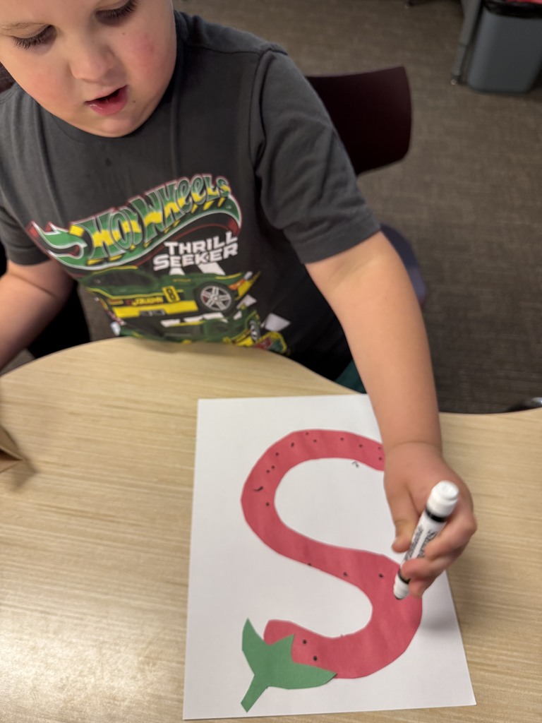 Student is drawing an S that looks like a strawberry.