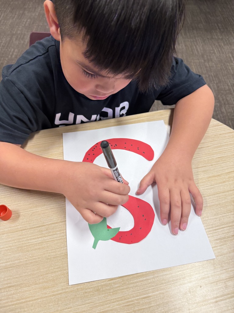 Student is drawing an S that looks like a strawberry.