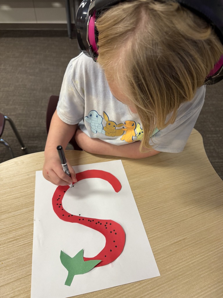 Student is drawing an S that looks like a strawberry.