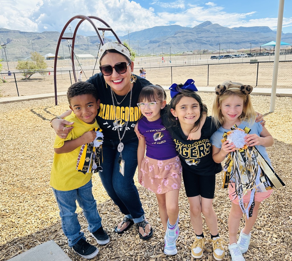Mrs. Wolfe with students wearing black, gold, and purple.