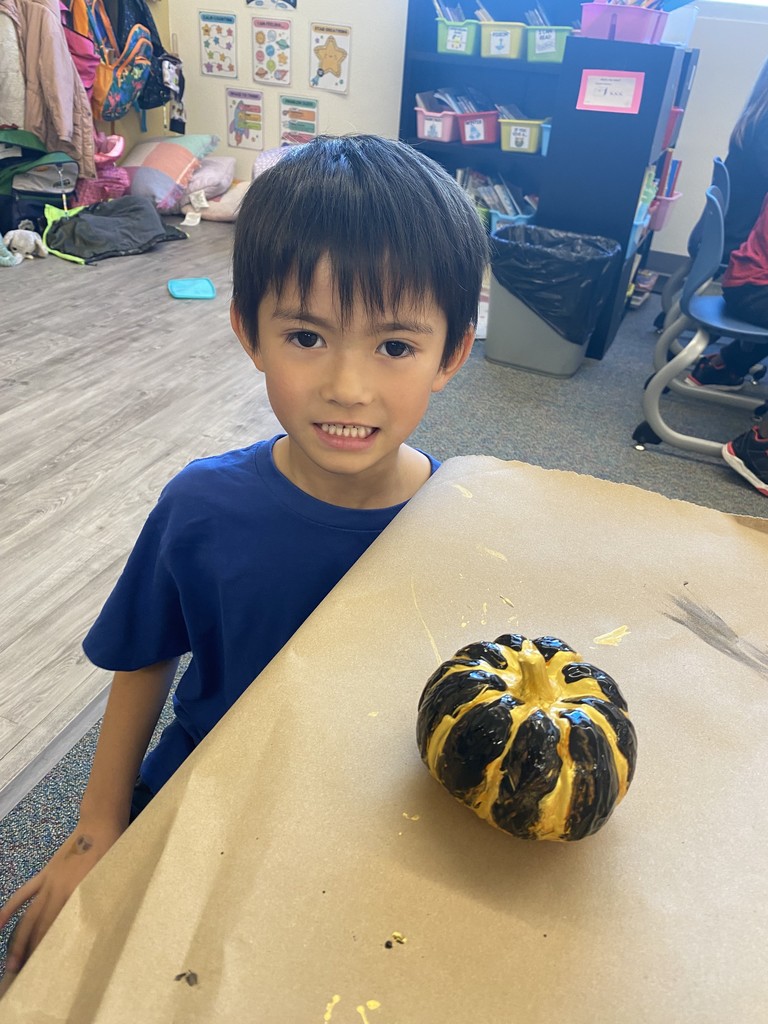 kid posing next to their painted pumpkin