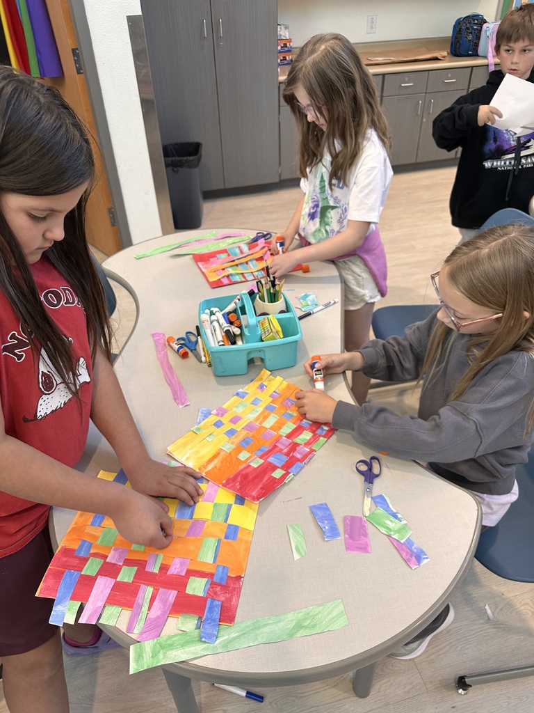 students focused on gluing different colored paper on their artwork