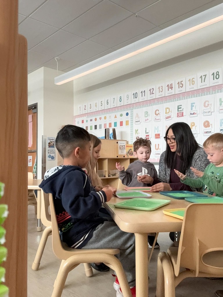teacher instructing students how to use the sand writting trays