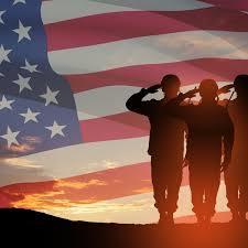Soldiers saluting an American flag with a sunset.