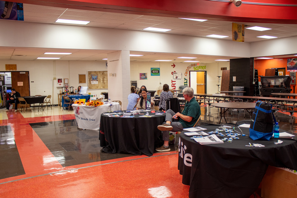 Vendor booth set up in middle school cafeteria with vendors talking to employees