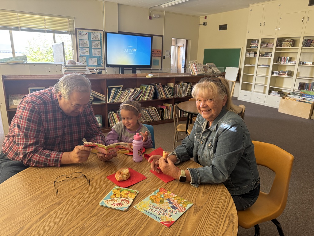 Student reading with grandma and grandpa in classroom
