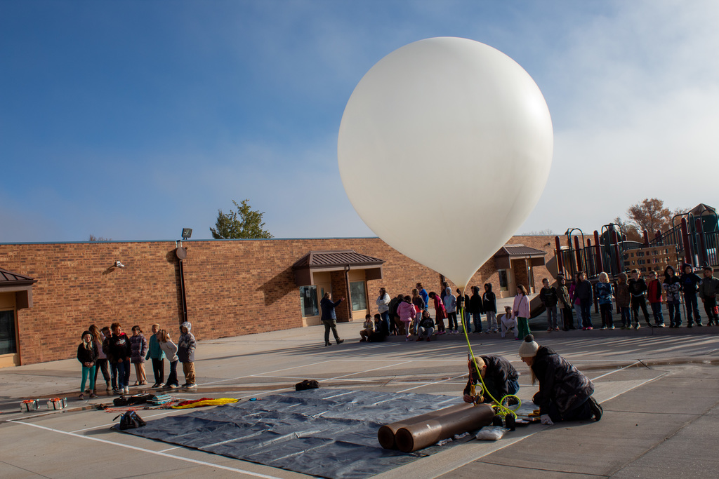 UW Staff filling up balloon while students observe