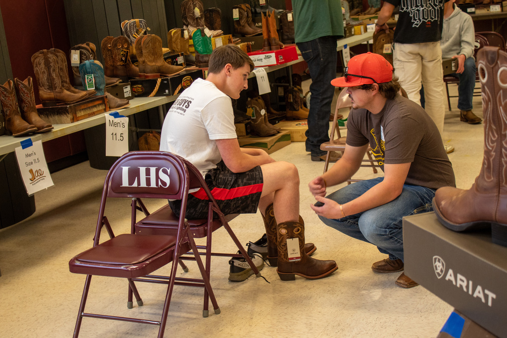 Student working with volunteer to try on boots