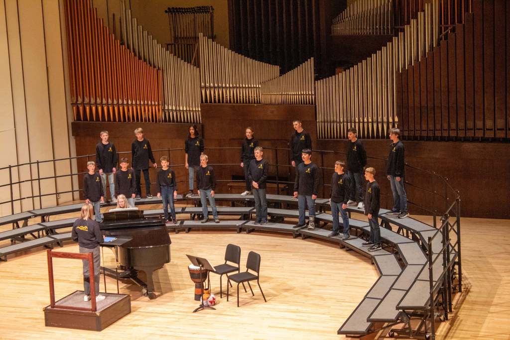 Middle school students standing on riser singing to audience