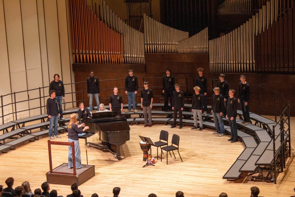 High school students standing on riser singing to audience