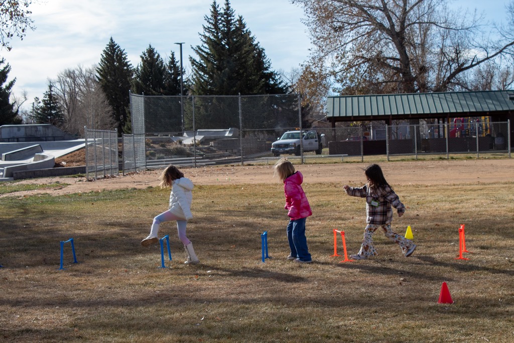 students running in a line jumping over hurtles