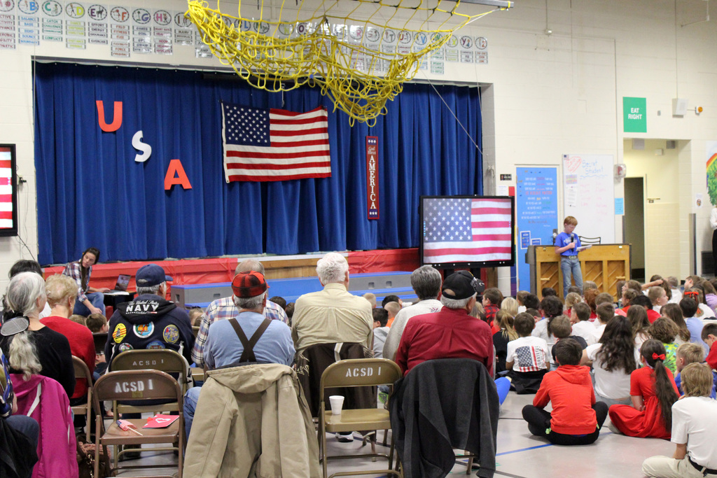 Student presenting at assembly to a crowd of staff, students, and veterans