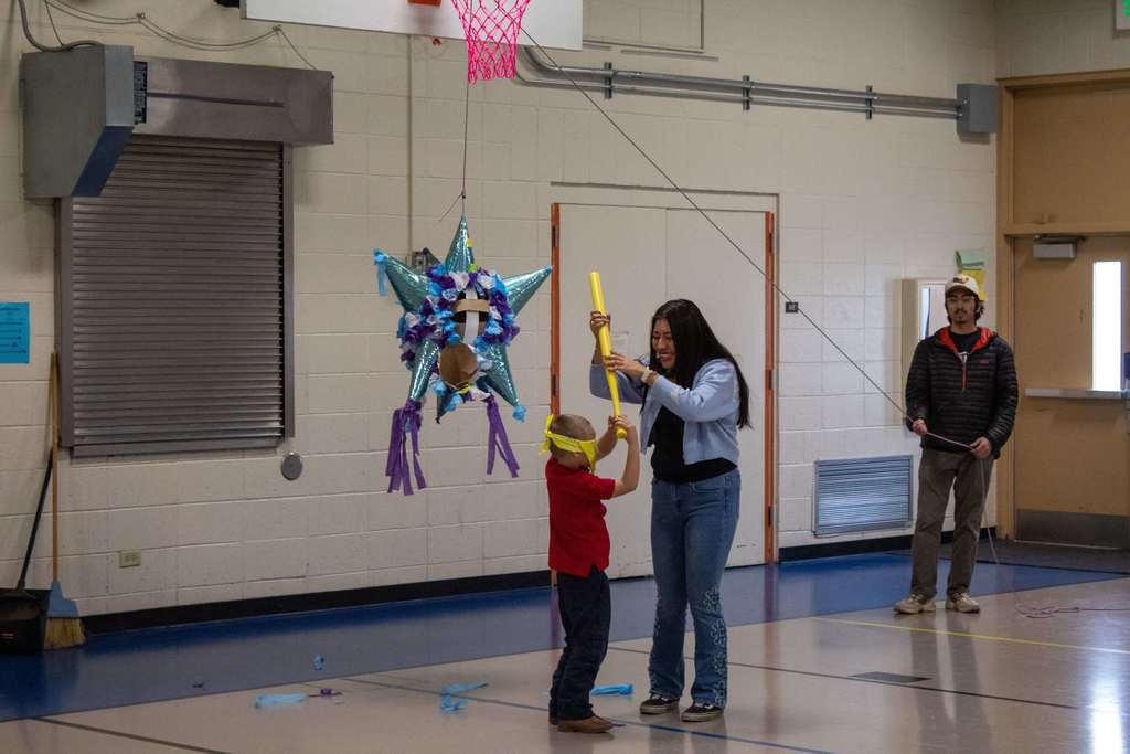 Student working with volunteer to hit the pinata