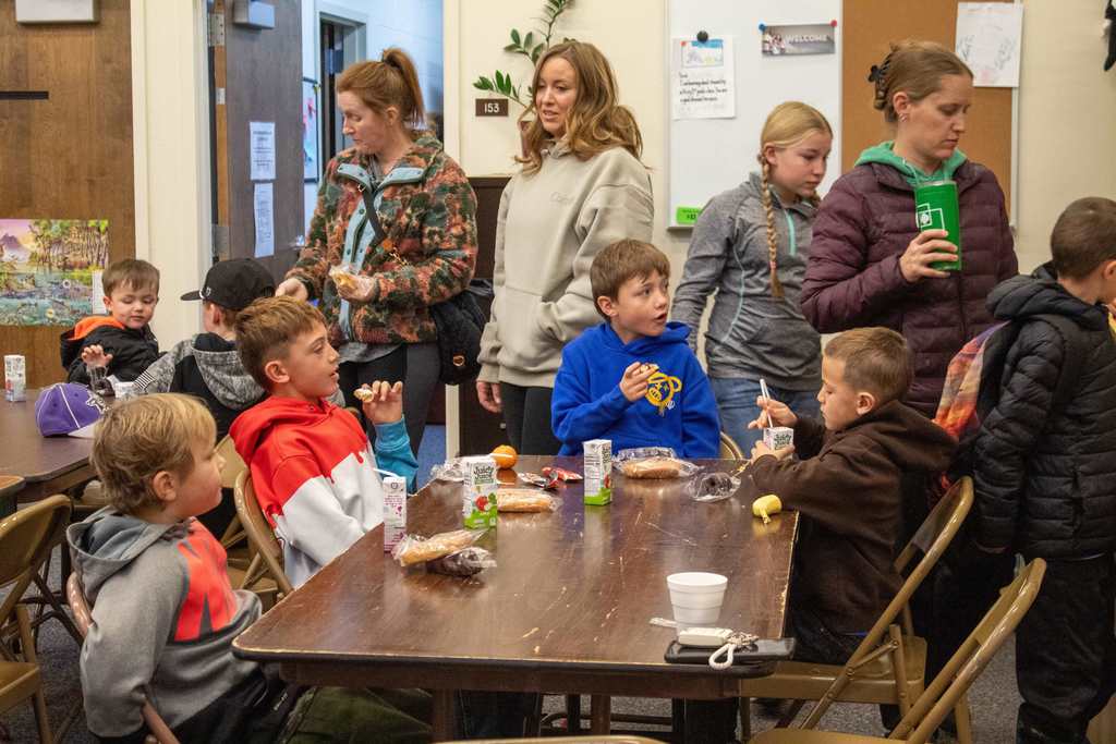 children sitting at a table talking while eating breakfast