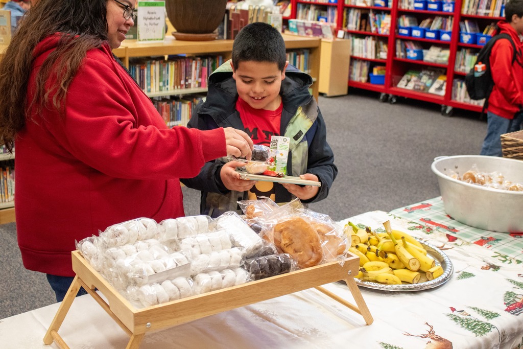 Child smiling while mother helps grab breakfat items from the table