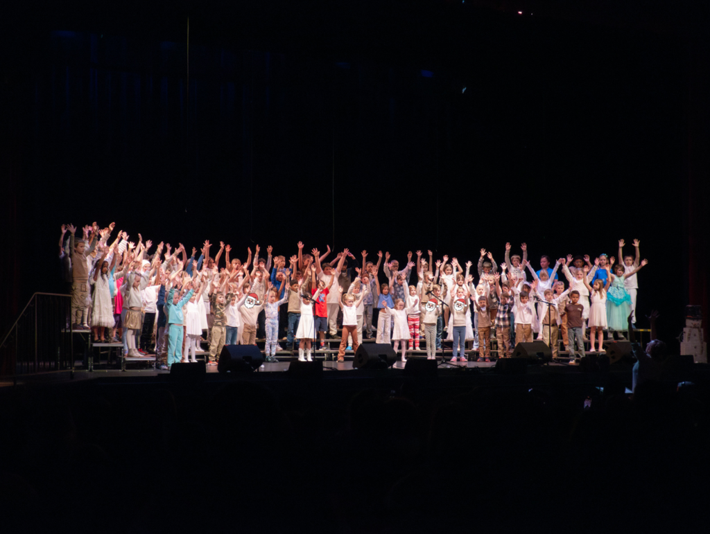 students singing on a stage dressed in winter costumes
