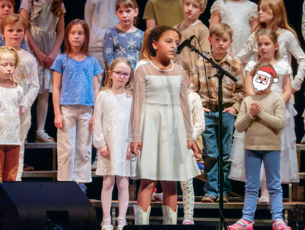 Student singing into microphone while classmates stand behind