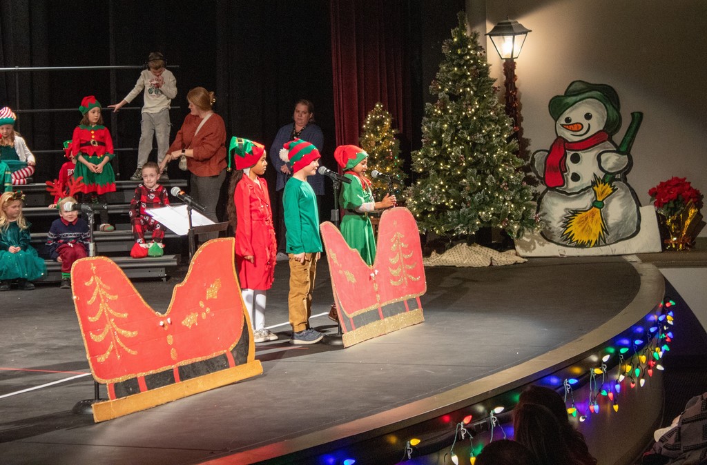 students standing behind cardboard sleigh dressed as gnomes
