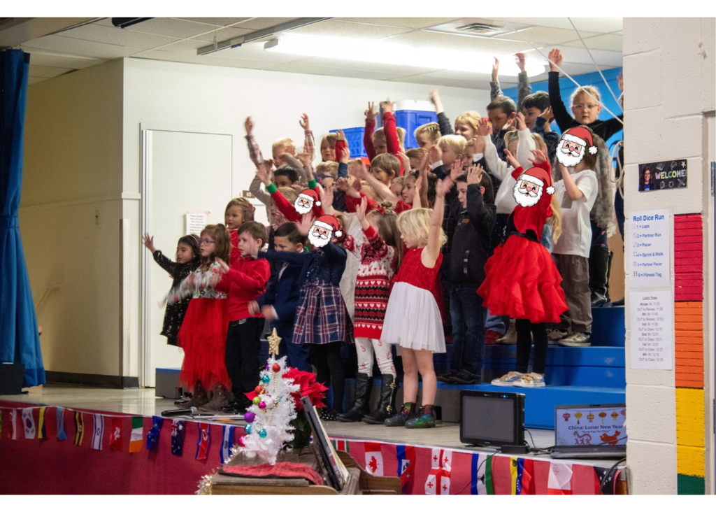 students standing on stage singing for a gym full of parents and staff