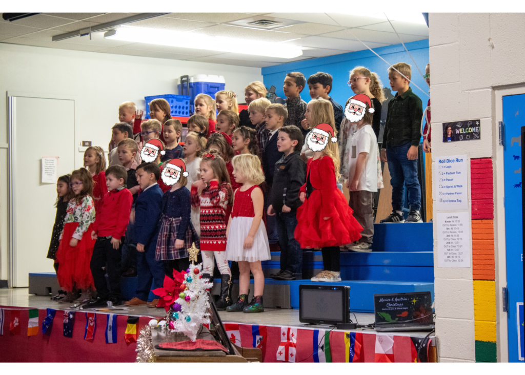 students standing on stage singing for a gym full of parents and staff