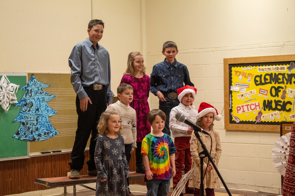 children on risers singing in front of a teacher conducting the music