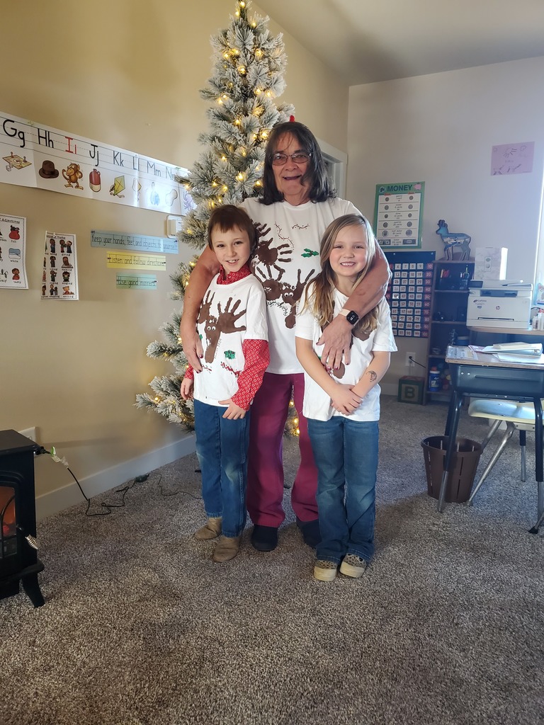 Young students posing with teacher in hand painted reindeer shirts