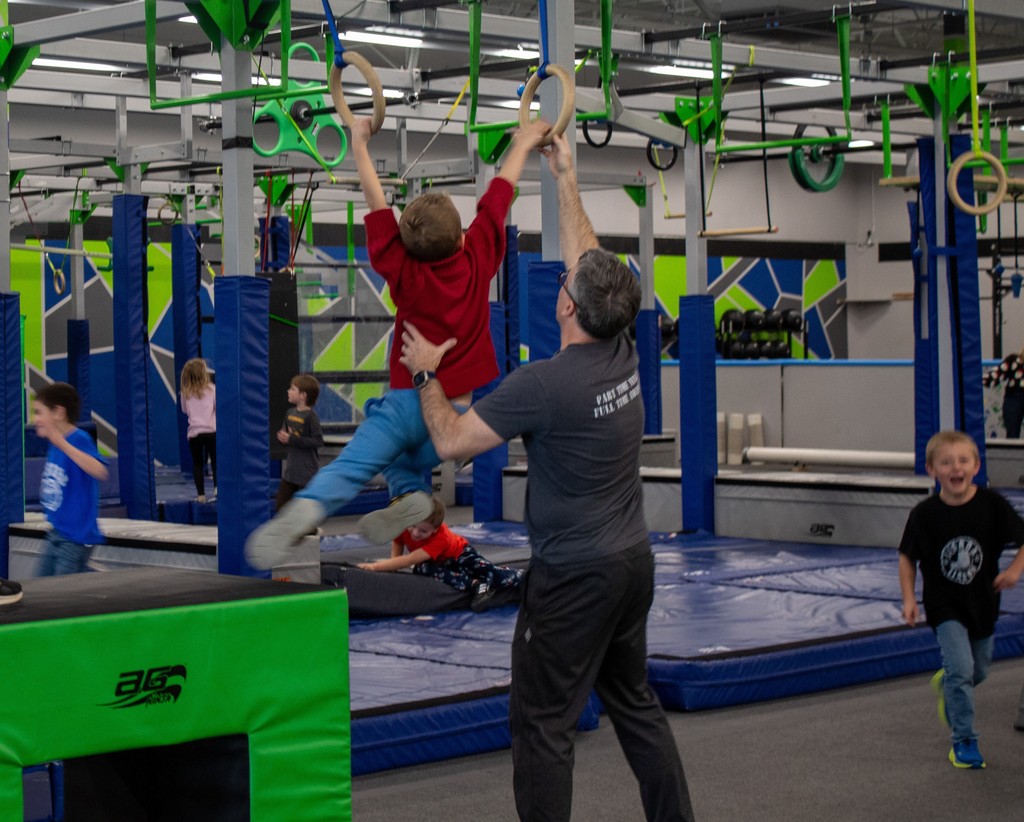student swinging on obstacle course rings