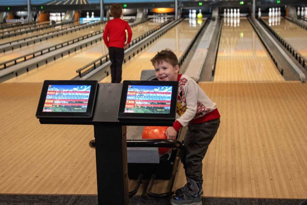 student smiling while grabing a bowling ball