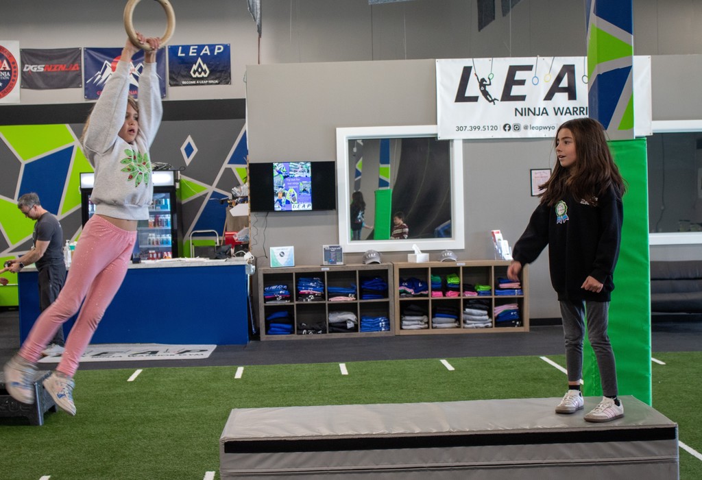 student swinging on obstavle course rings