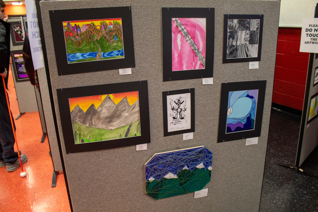 student paintings haning on the wall on display