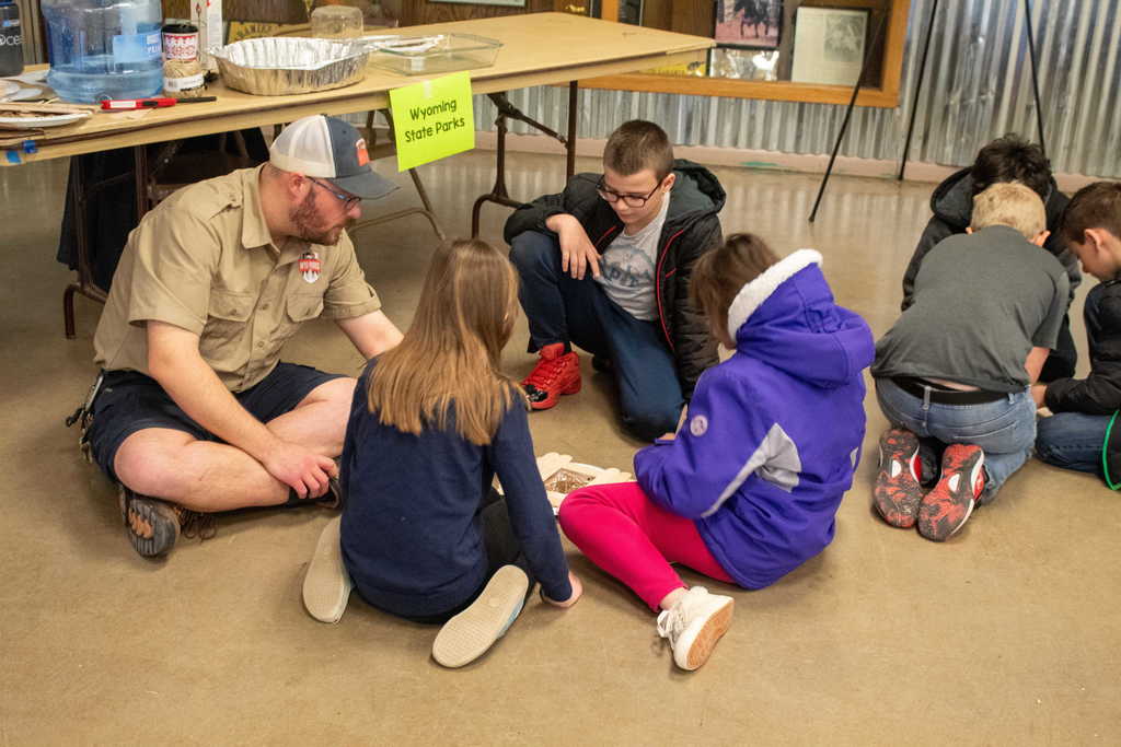 Young student sitting with instructor to make a fire