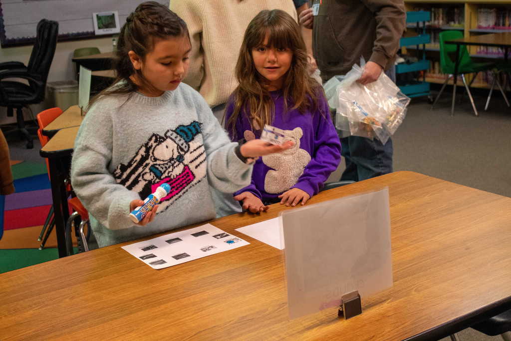 Two young girls with brown hair amaylizing pieces of paper