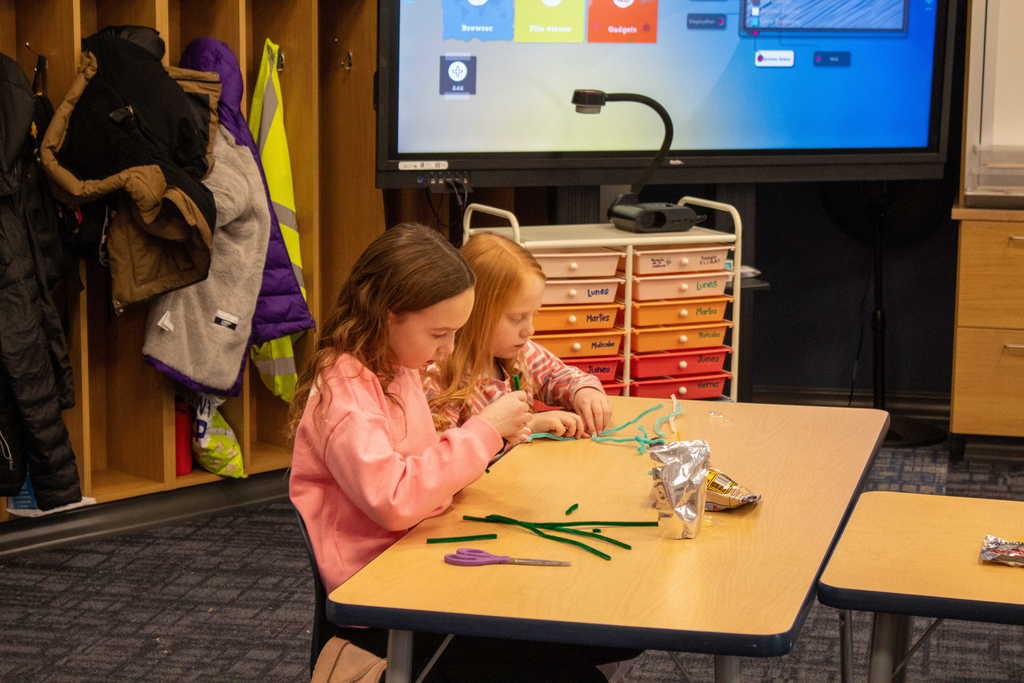 two young girls making crafts with pipe cleaners
