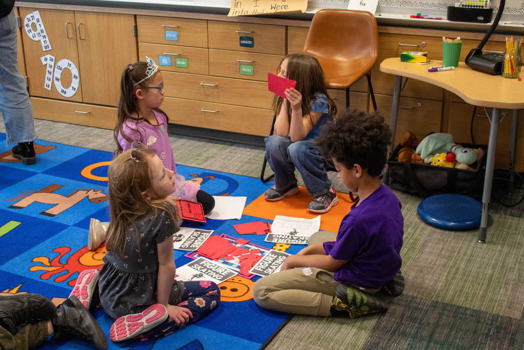 four students sitting in a circle playing a game